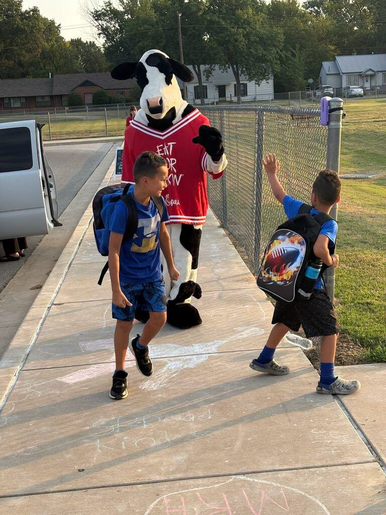 Students waving at cow