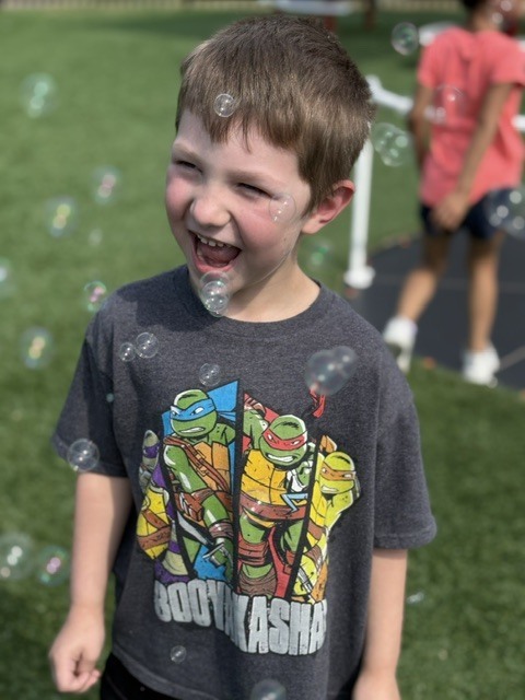 student smiling with bubbles all around him