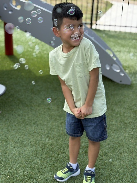 student smiling with bubbles all around him