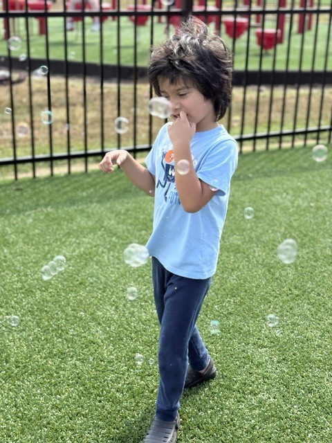 student smiling with bubbles all around him