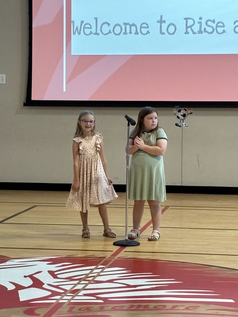 Two girls standing and smiling at the microphone
