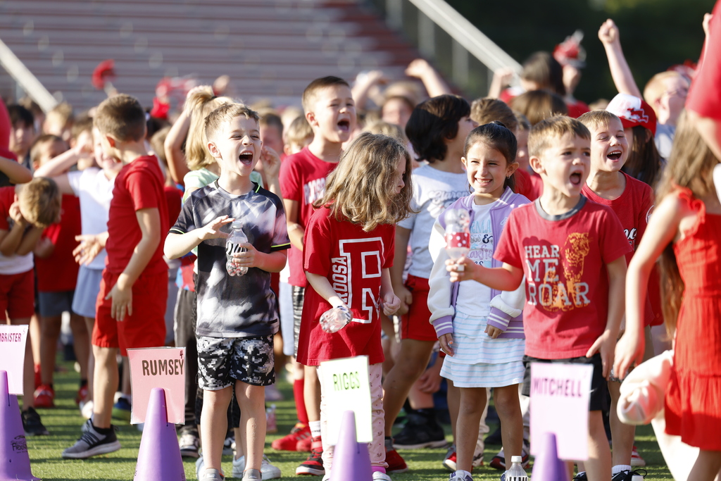 Elementary students cheering at a homecoming rally.