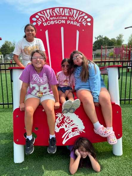 5 girls sitting on large red chair smiling