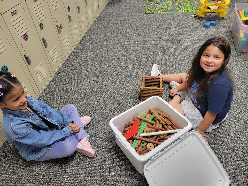 two girls building with logs