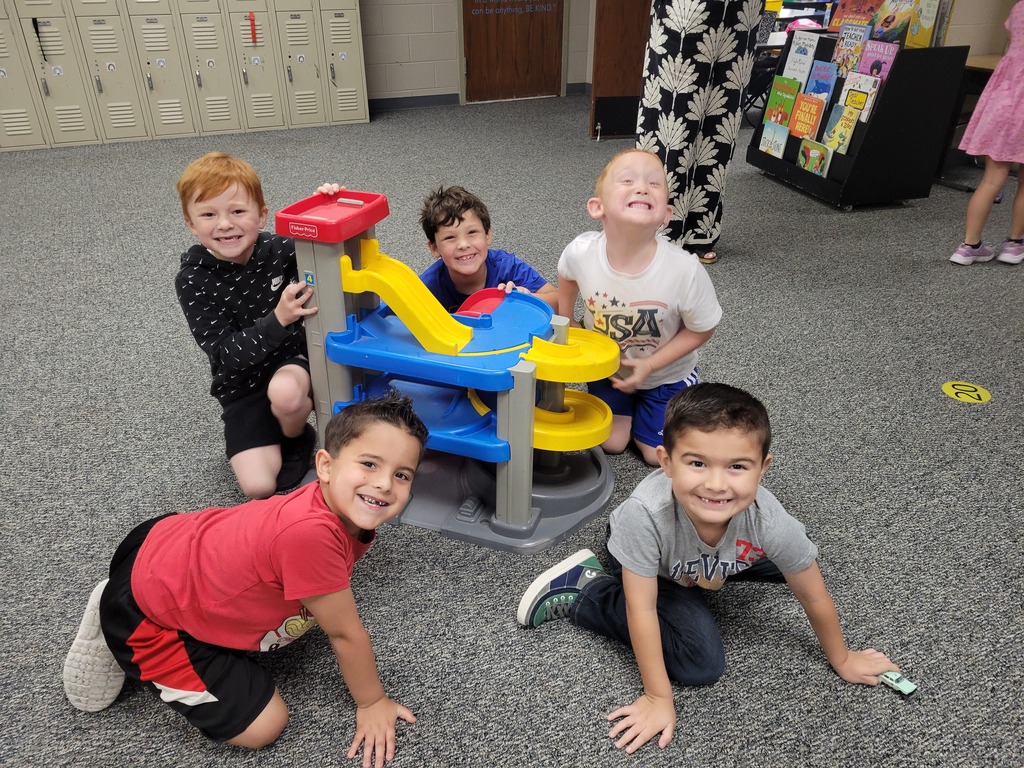 5 boys smiling and playing with cars