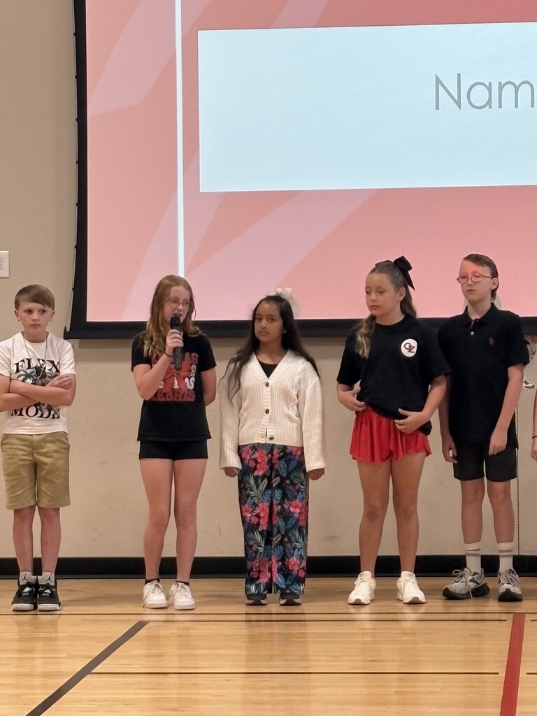 5 students standing at the front of the gym