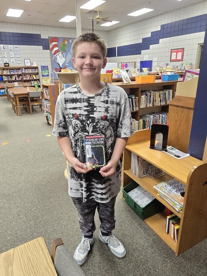 student in library holding a book that says terror on the titanic
