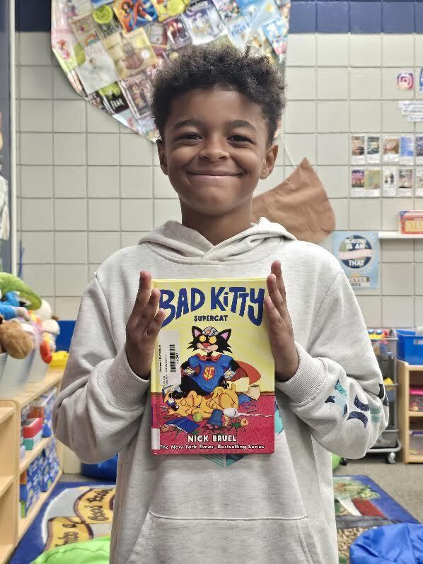 student holding book, smiling