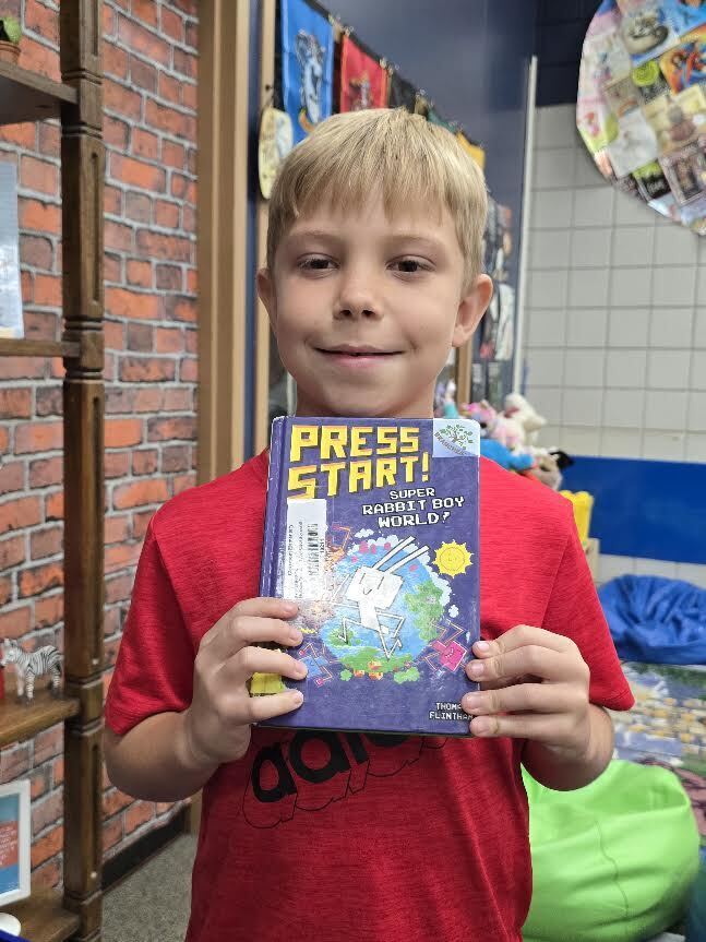 student holding book, smiling