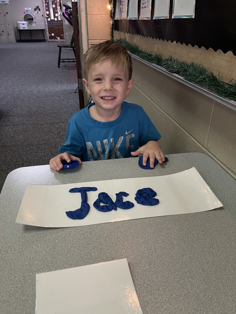 student holding playdoh smiling