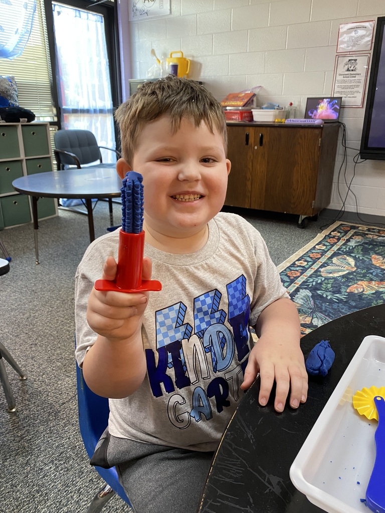 student holding playdoh smiling