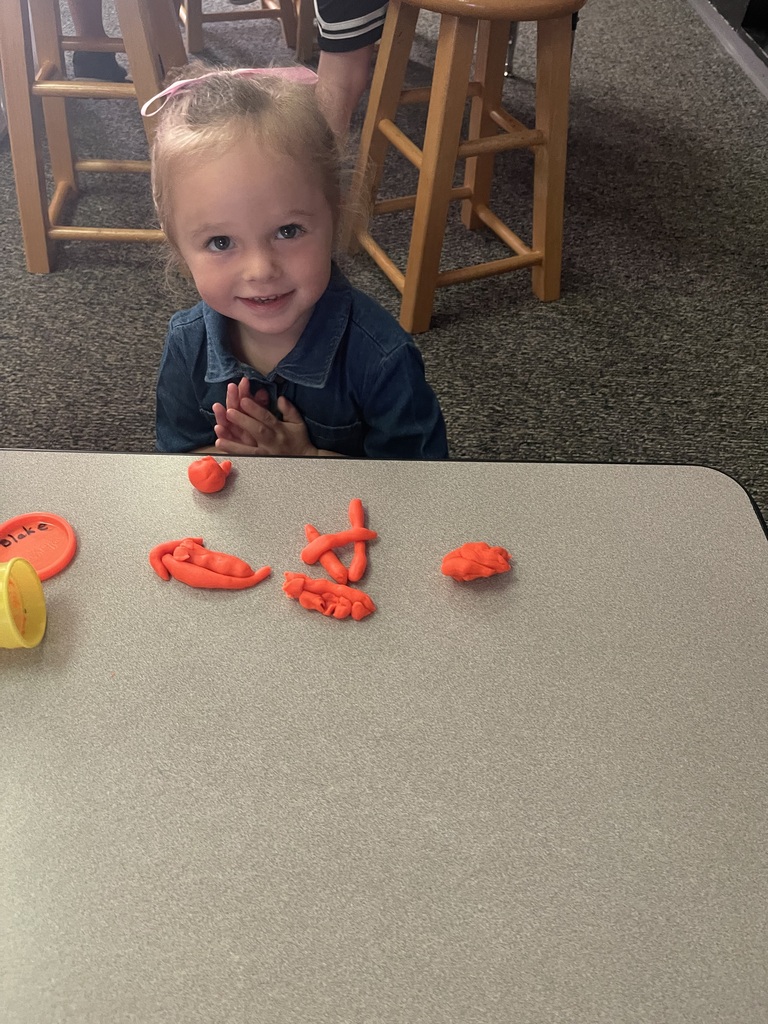 student holding playdoh smiling