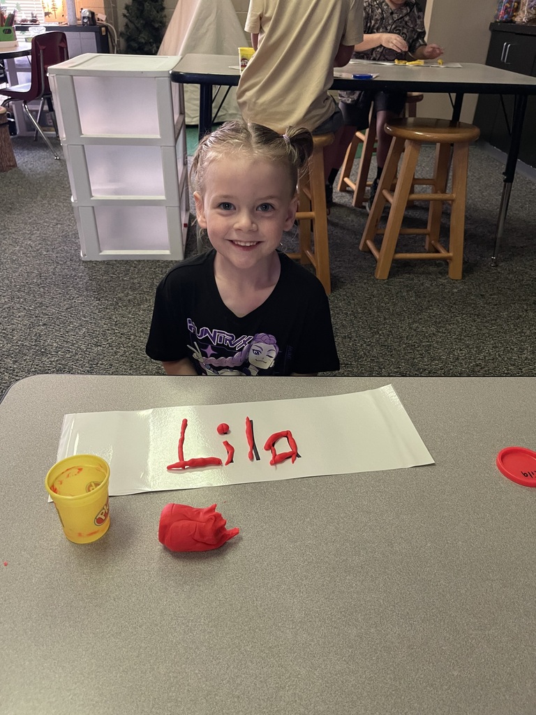 student holding playdoh smiling