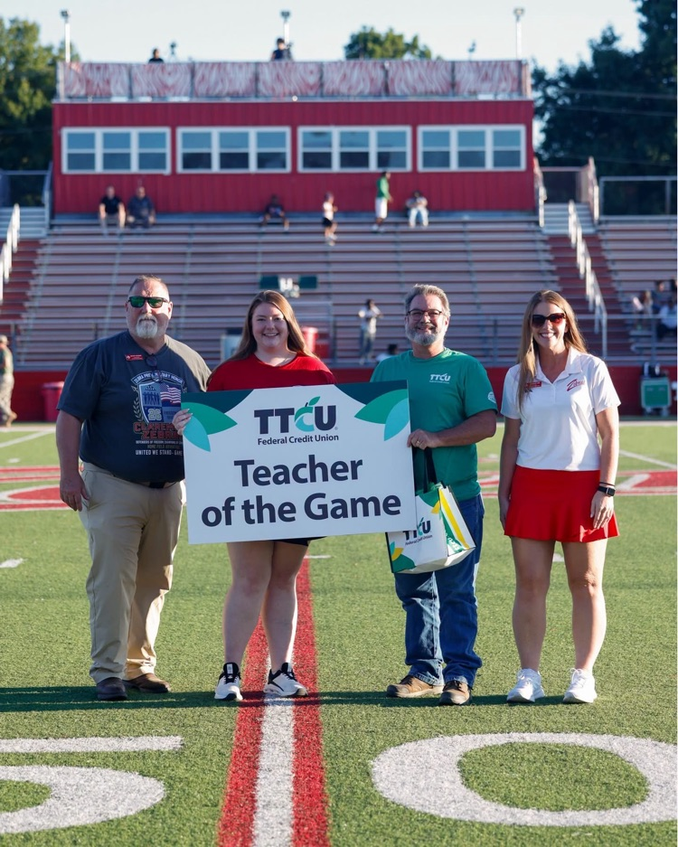 Teacher of the game receiving award on the field. 