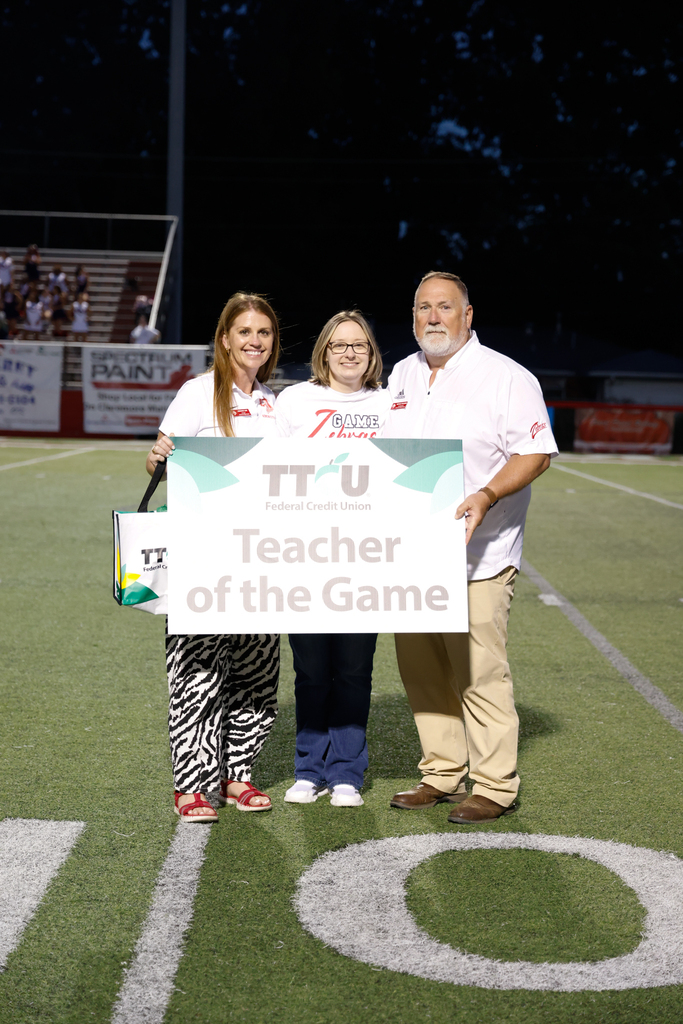 Sarah Gray with Brooke Lee and Bryan Frazier on the field with TTCU teacher of the game sign