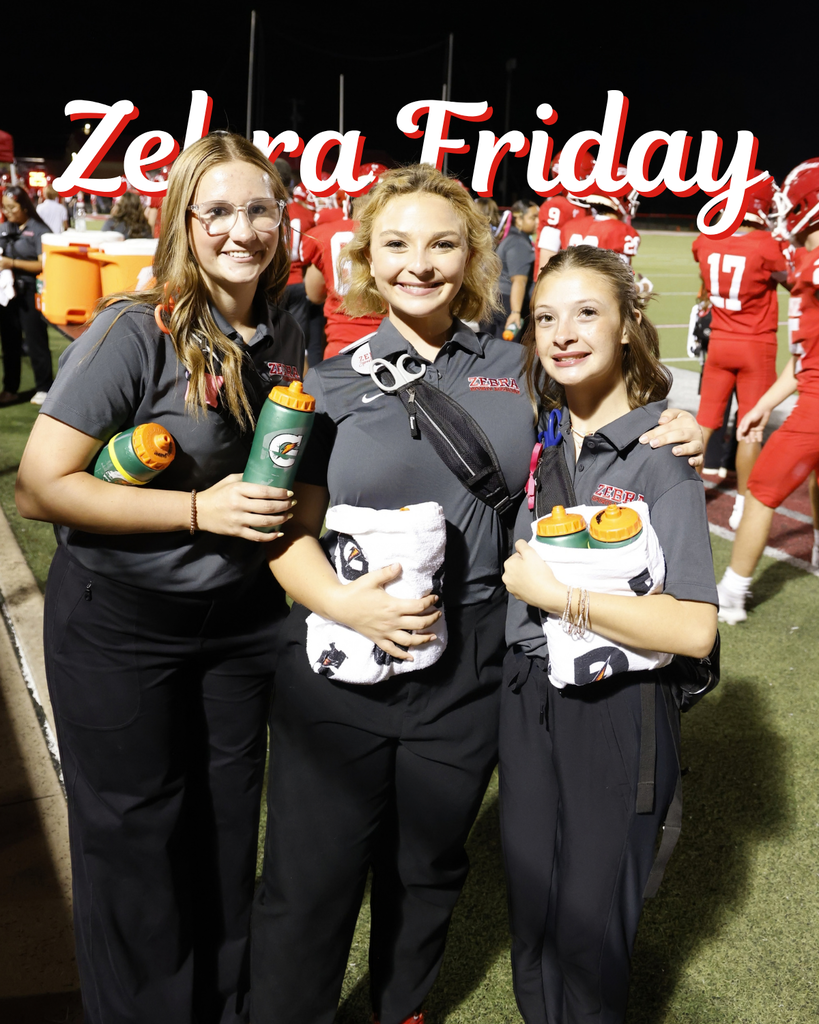 Three Zebra student athletic trainers smile on the football sideline.