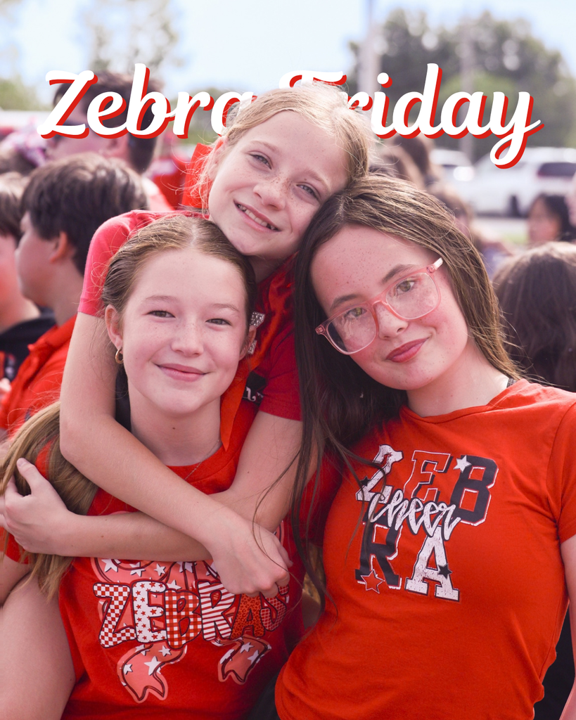 Three elementary students smile together in Zebra spirit wear.