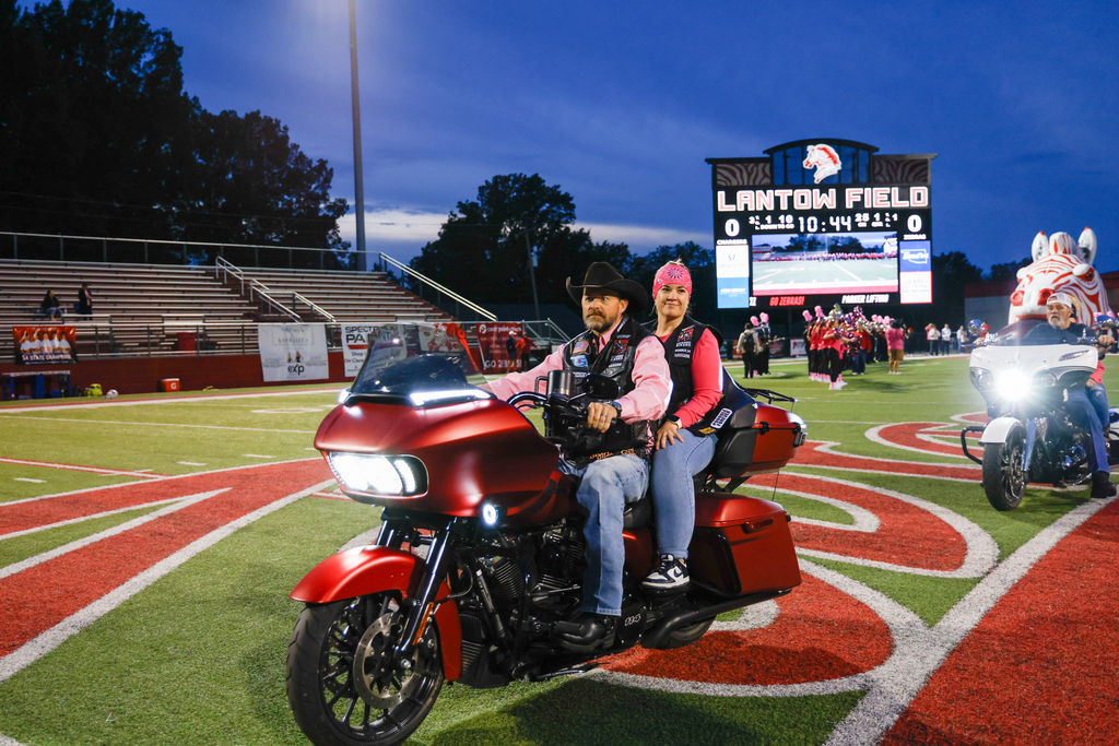 Pink Out honorees ride motorcycles across Lantow Field.