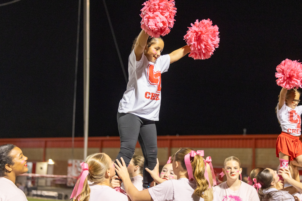 CYFA and Zebra cheerleaders perform a stunt with pink pom-poms during Pink Out.
