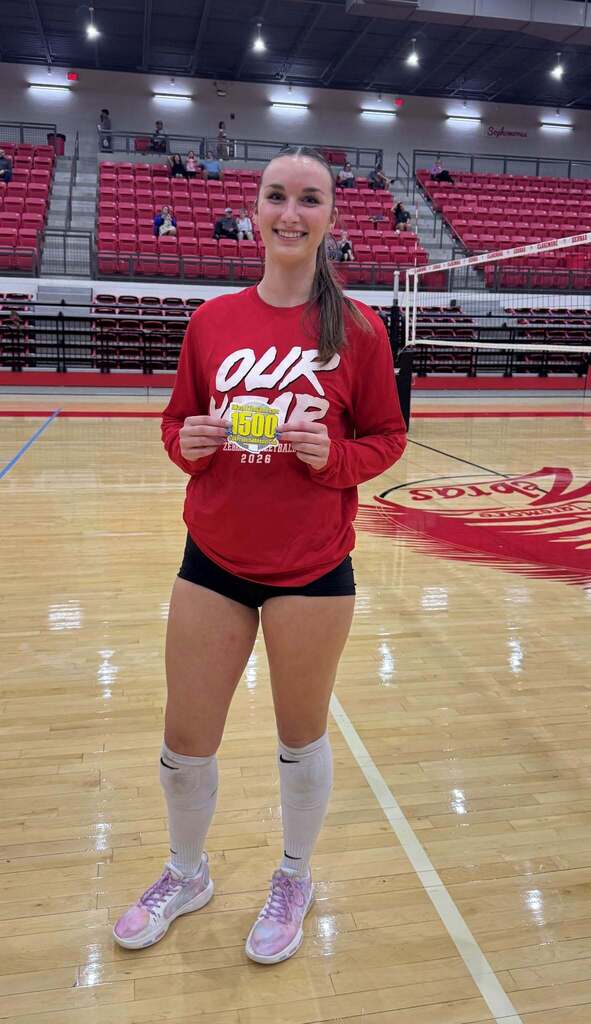 Grace Baughman holds her 1,500 career assists milestone sticker on the volleyball court.