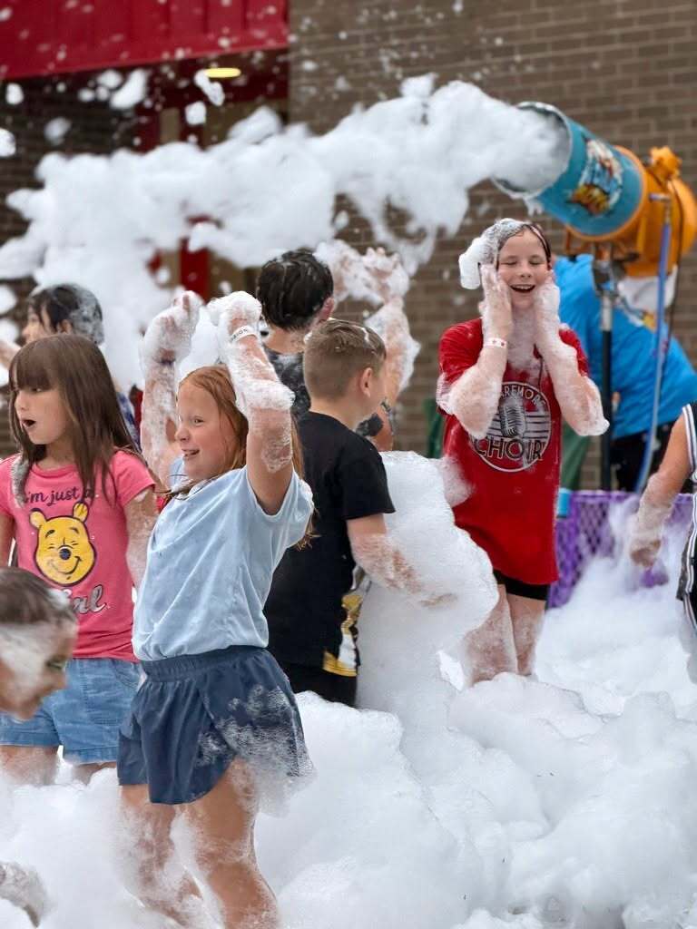 Students laugh and play in foam during Roosa PTO’s Fall Festival.