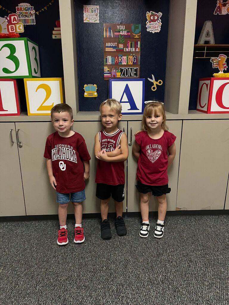 Three students showing off their college team gear.