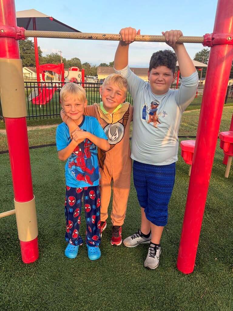 Three students dressed in pajamas on the playground.