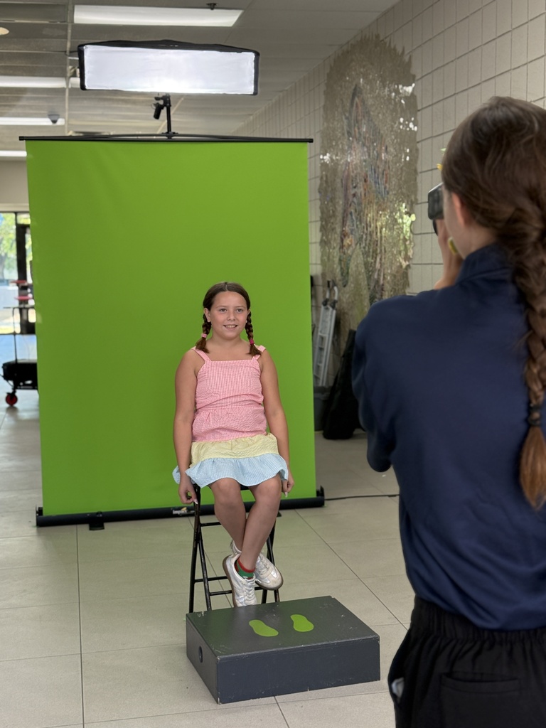 student getting photo taken in front of green screen