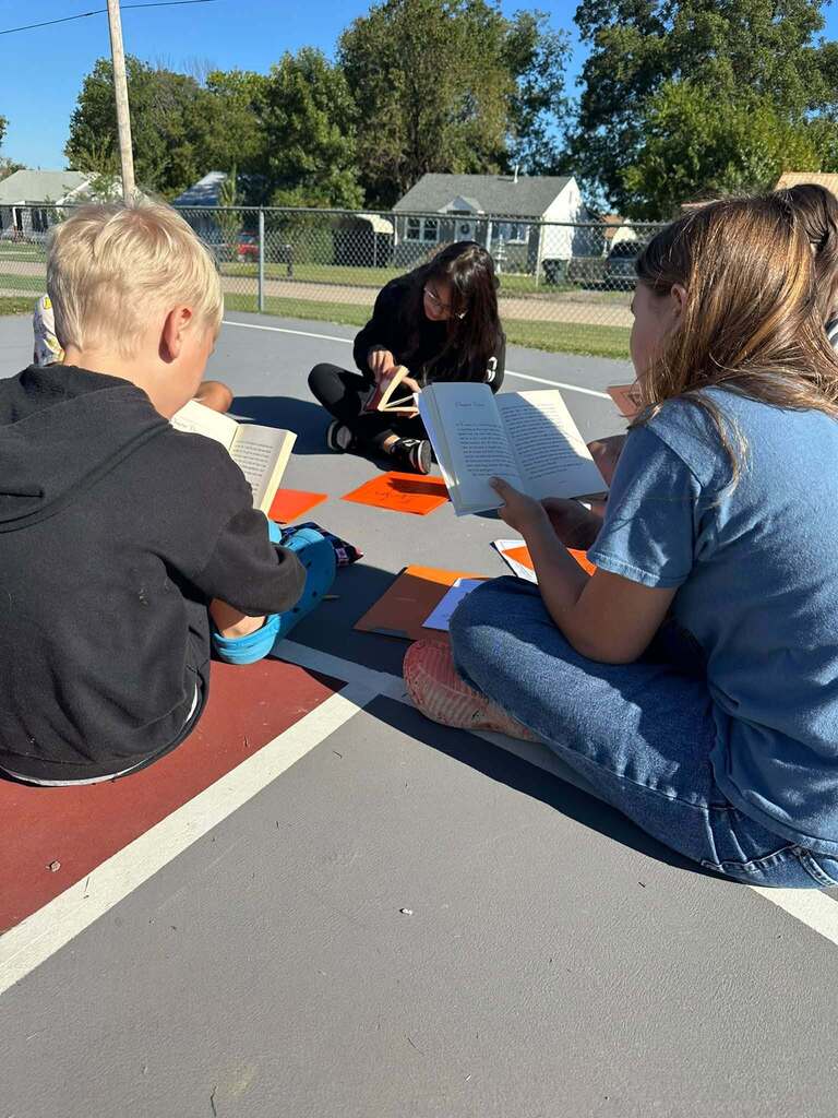 students sitting on basketball court reading books together