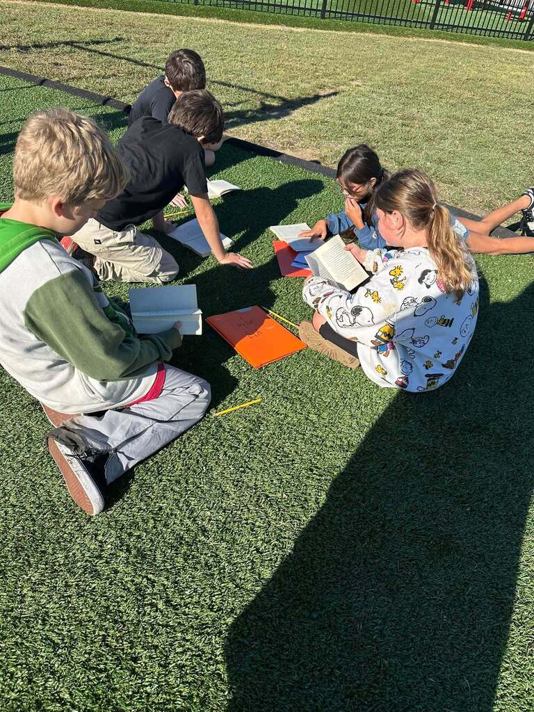 students sitting on grass reading books together
