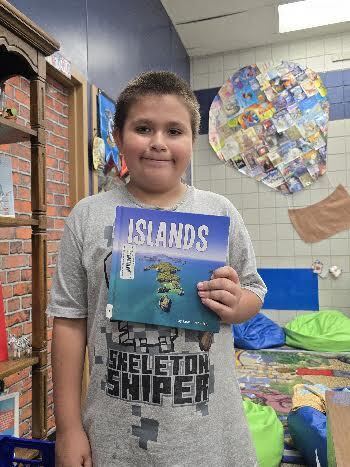 student holding book called islands and smiling