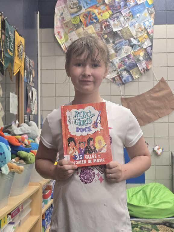 student holding book titled rebel girls rock