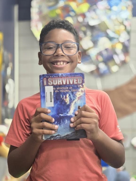 student holding an I survived book smiling