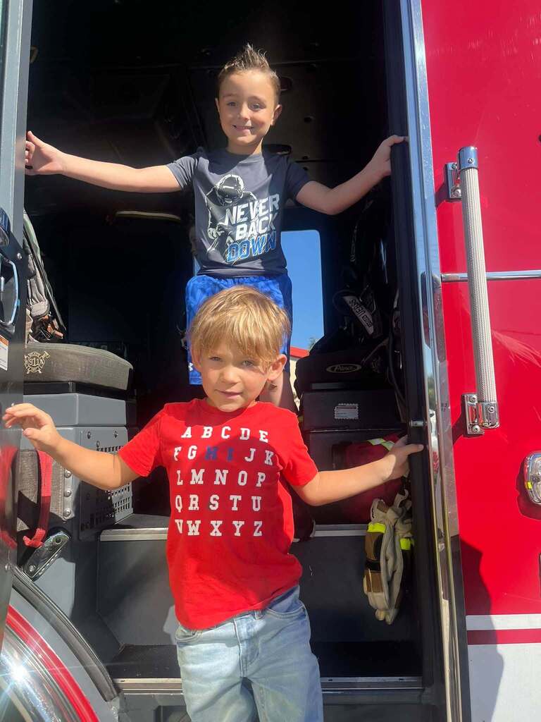 Two students pose in the doorway of a fire truck.