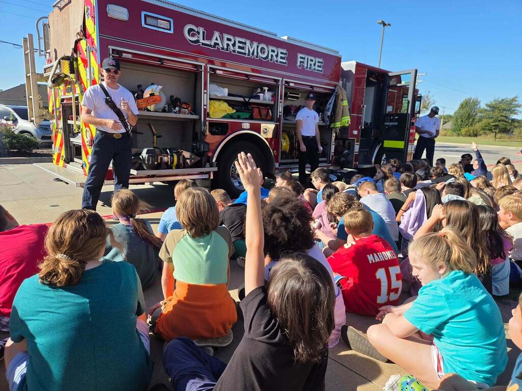Firefighter teaches students about equipment on a fire truck.