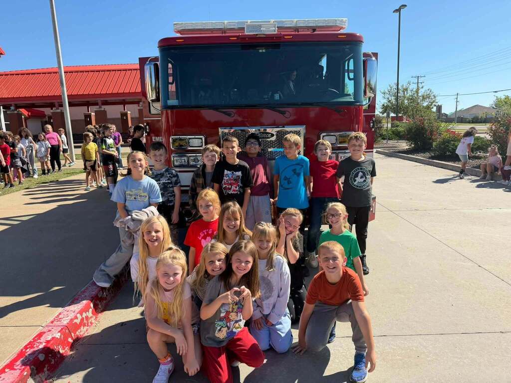 Students pose for a group photo in front of a fire truck.