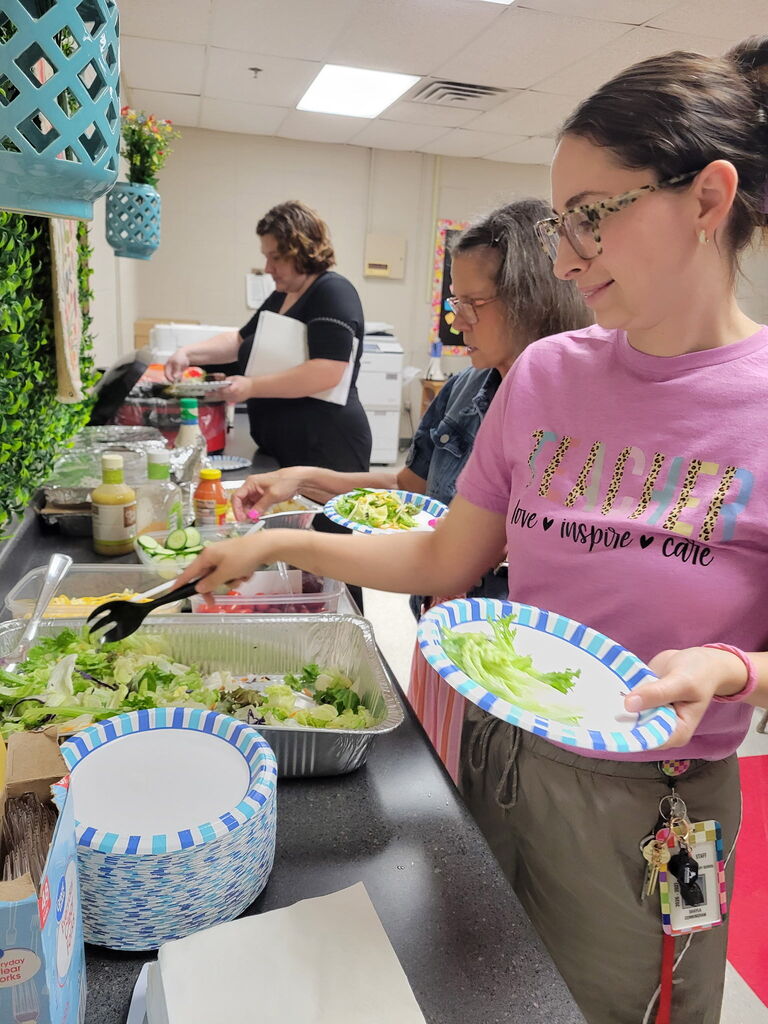 3 staff members getting food like salad and green beans