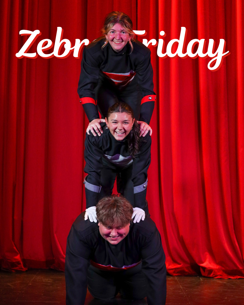 Three band members pose in a stacked formation in front of red curtains.