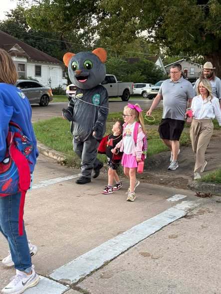 students and dressed up cat or mouse walking to school