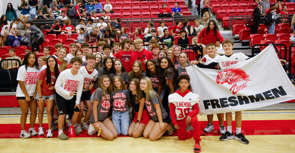 CHS freshmen pose together in the gym, holding a large white Claremore Zebras Freshmen flag.