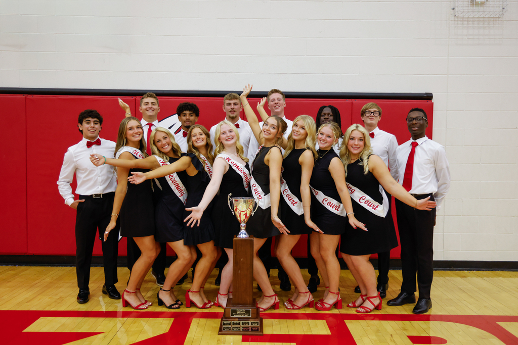 CHS Homecoming Court members pose around the Homecoming trophy in formal black, white, and red attire.