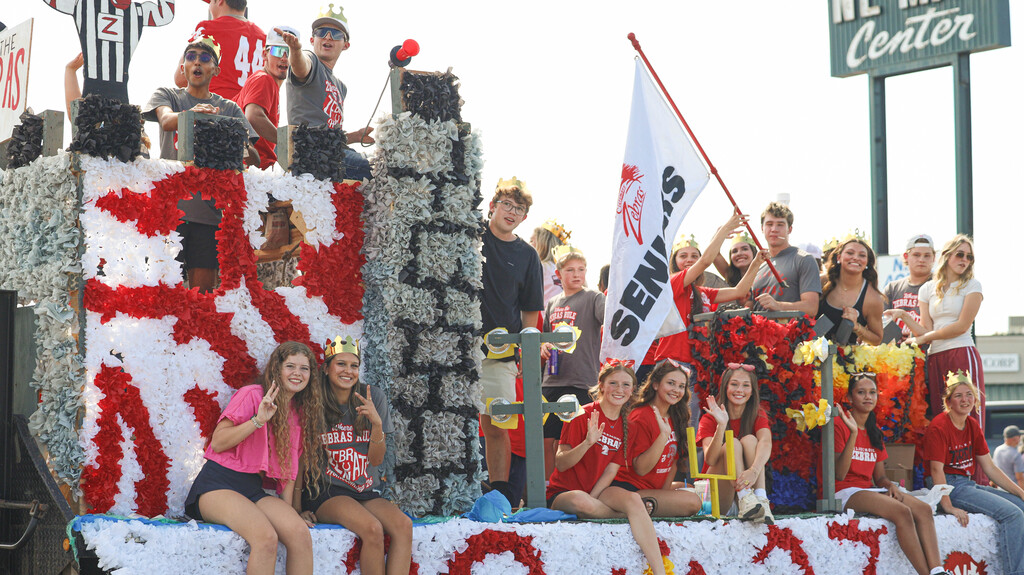 CHS students wearing crowns ride a decorated senior class float.