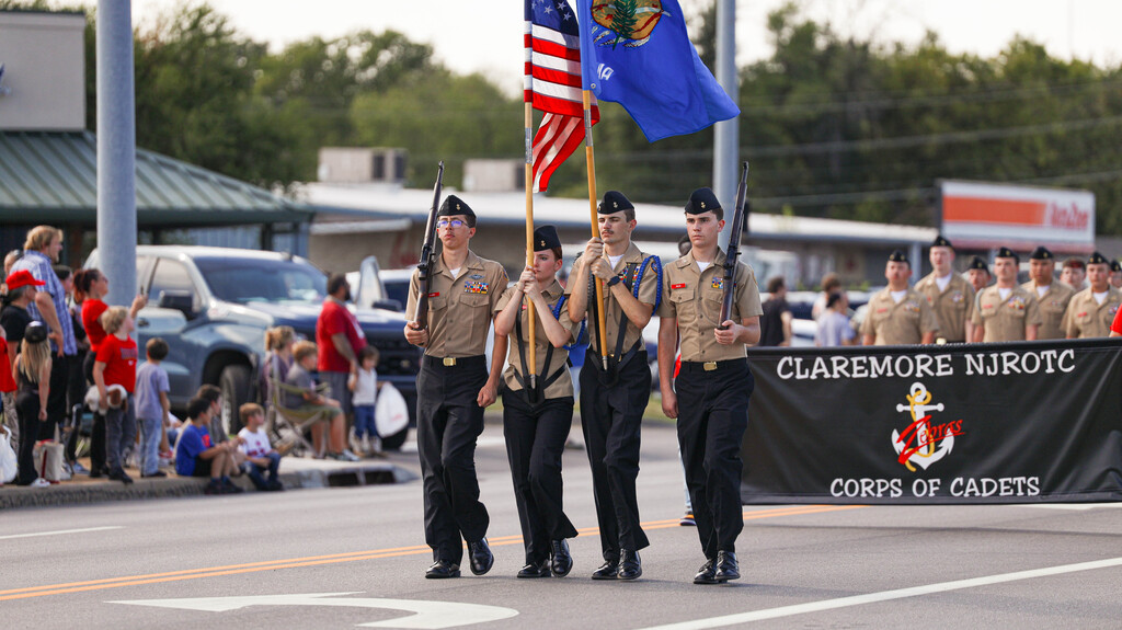 Claremore NJROTC cadets march in the Homecoming parade carrying flags and rifles.