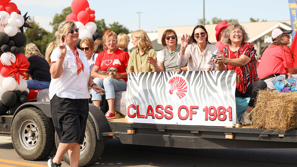 Members of the Class of 1981 wave from their decorated reunion float.