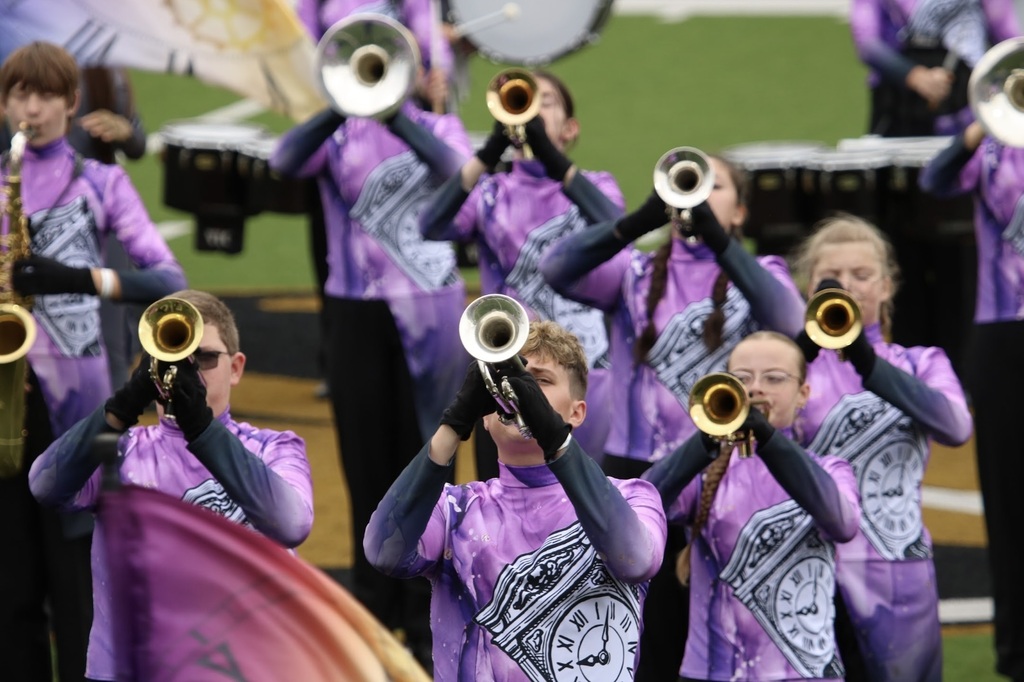 Zebra Band brass players perform in their purple, clock-themed uniforms during a marching competition.