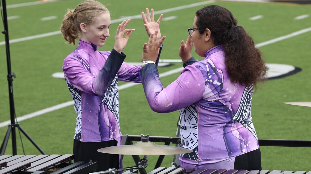 Two Zebra Band percussionists doing a handshake before performance.