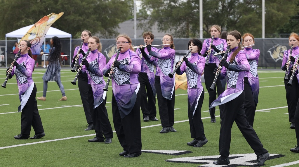 Zebra Band woodwind players perform in formation on the field.