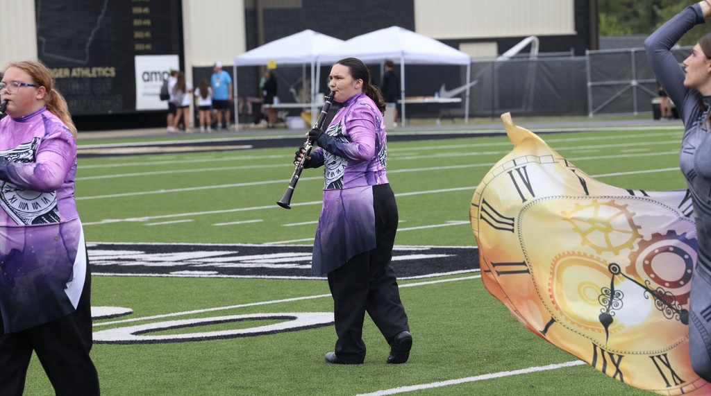 A Zebra Band clarinet player performs beside a color guard member with a clock-themed flag.