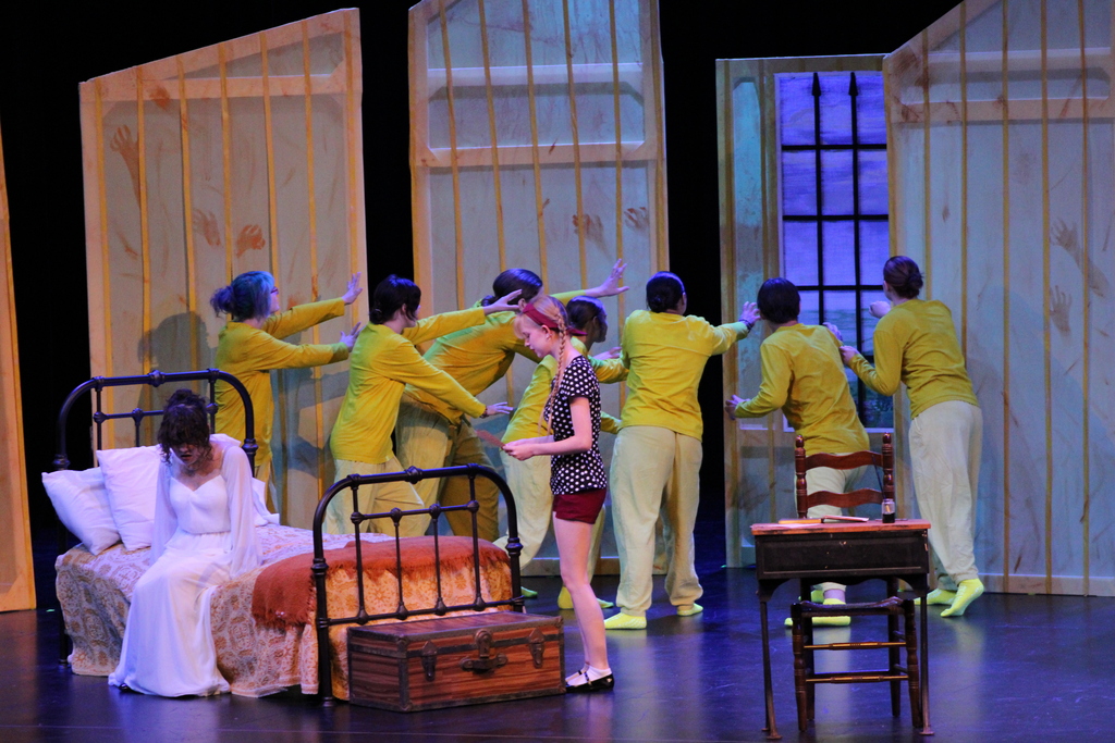 Student actors perform a scene involving a bedroom and wallpaper-covered walls.