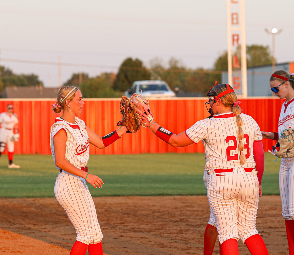 Two Claremore softball players high five with their gloves